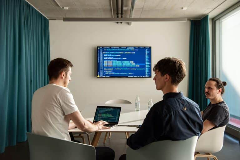 WordPress Agentur Gruppenfoto der dreiQBIK GmbH: Joscha Holzhäuer, Moritz Bappert und Lennart besprechen WordPress-Programmierung im Konferenzraum im FUX in Karlsruhe