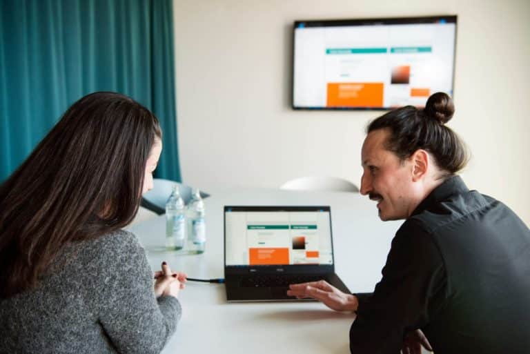 WordPress-Webdesigner Lennart Schleifer bespricht im Konferenzraum mit einer Kundin das WordPress-Webdesign