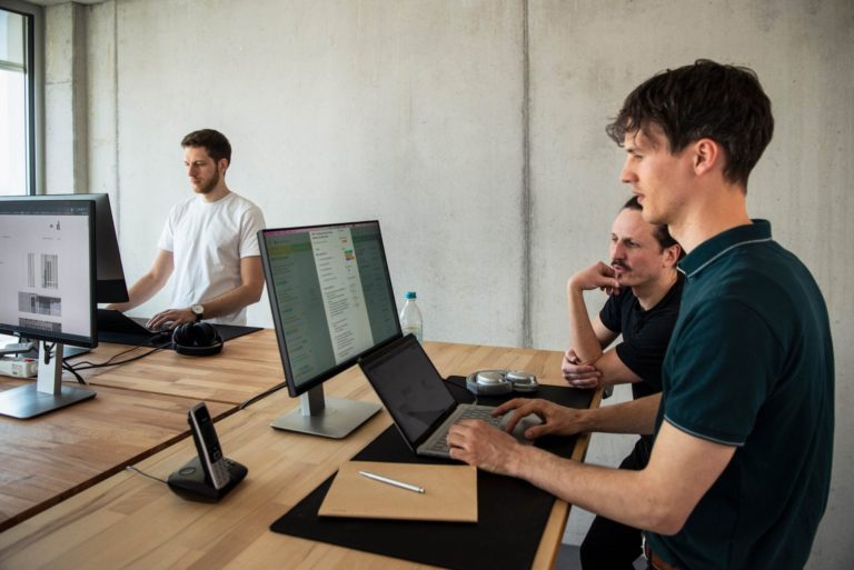 WordPress Agentur Gruppenfoto der dreiQBIK GmbH: Joscha Holzhäuer Lennart Schleifer und Moritz Bappert im Büro im Gespräch