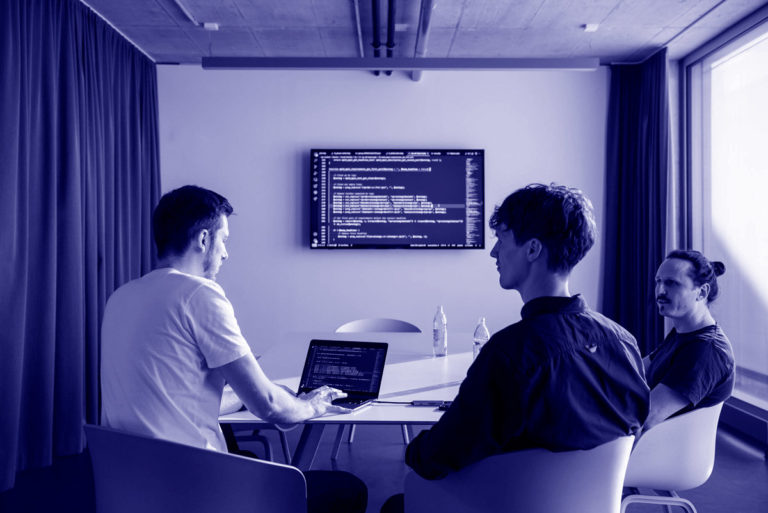 WordPress Agentur Gruppenfoto der dreiQBIK GmbH: Joscha Holzhäuer, Moritz Bappert und Lennart besprechen WordPress-Programmierung im Konferenzraum im FUX in Karlsruhe